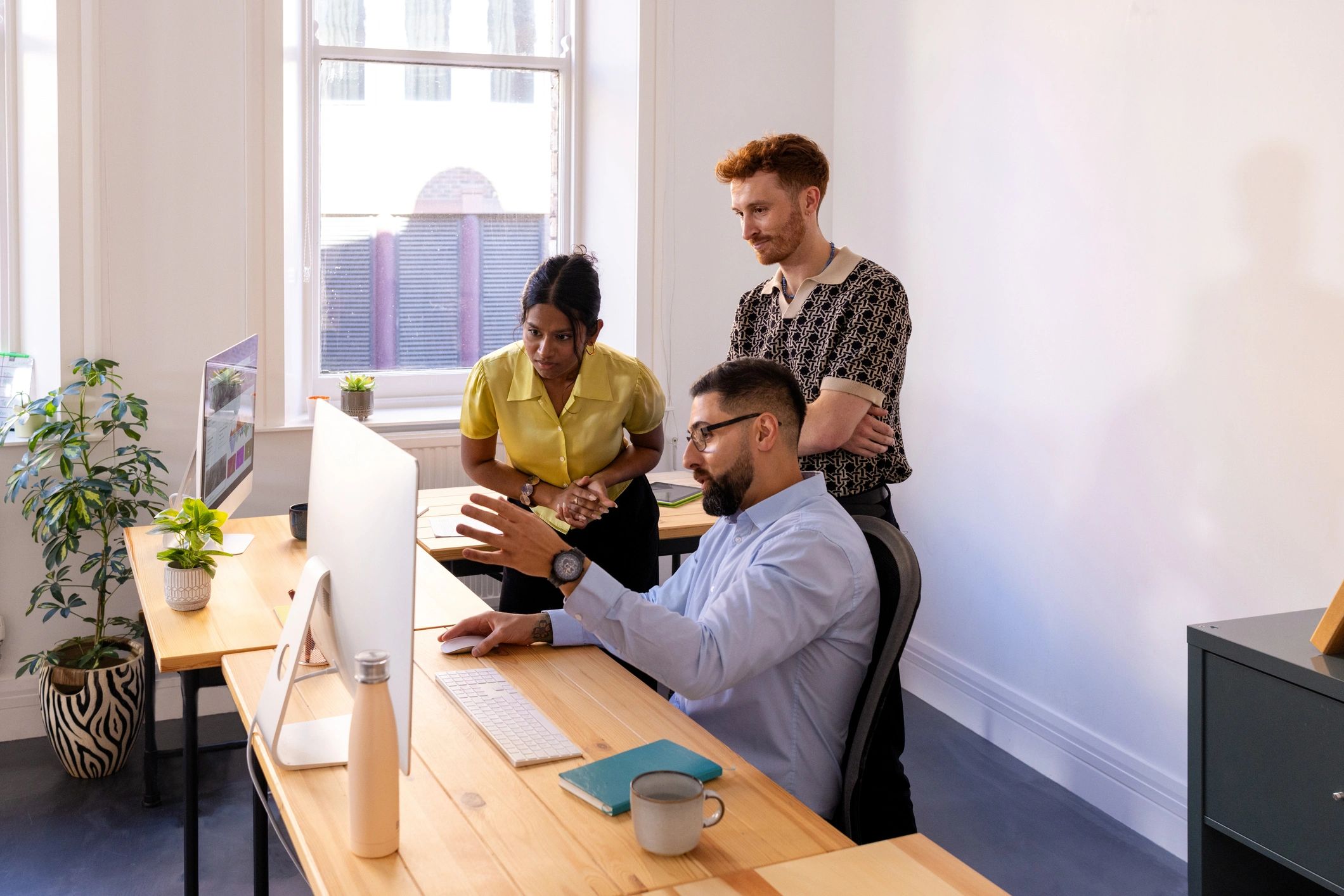Team members discussing ideas around a computer in a modern office